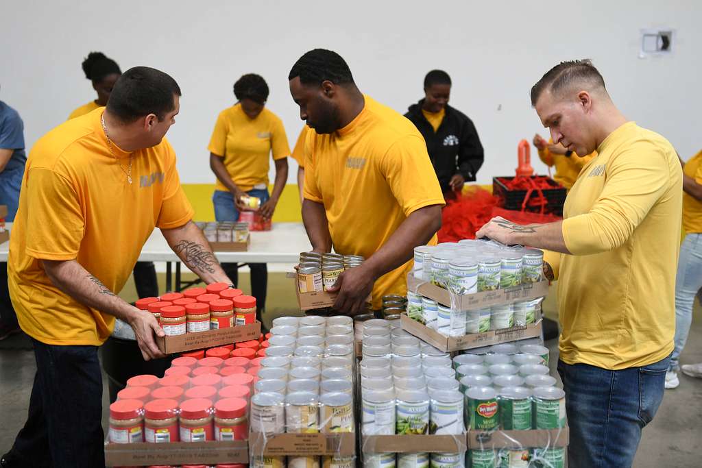 Chief Damage Controlman Derek Esqivel, left, Damage Controlman 2nd Class Scott Barr and Religious Programs Specialist 2nd Class James Brantley, help bag canned goods at the San Diego Food Bank during San Diego Fleet Week (SDFW) 2018.