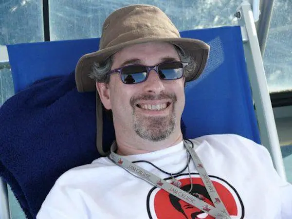 David Nolan wearing sunglasses, smiling, lounging in deck chair wearing Jam Cruise ID card.