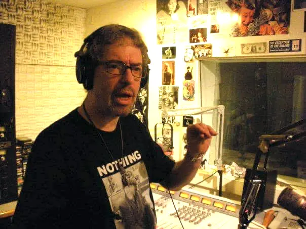 David Nolan, wearing headphones in studio, speaking.