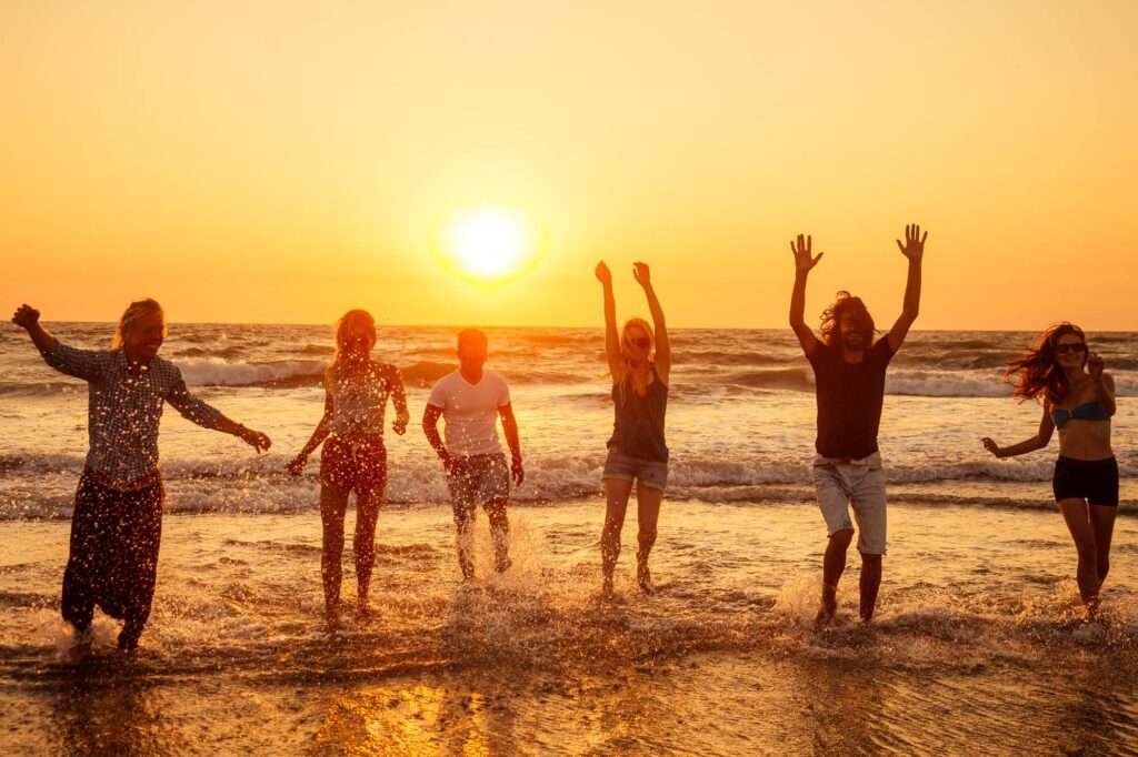 Joyful friends celebrating sobriety together at sunrise on the beach - We Stopped Drinking!